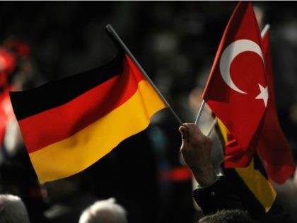 A visitor holds a Turkish and a German flag during a Turkish cultural event where Turkish Prime Minister Recep Tayyip Erdogan was expected on February 27, 2011 at the ISS Dome venue in Duesseldorf, western Germany. The event was organised by the Turkish 'Committee for Turks living abroad and related …