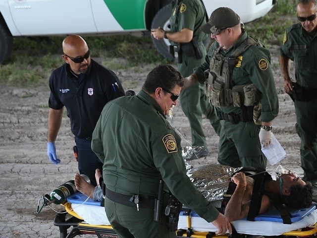 MCALLEN, TX - AUGUST 07: Paramedics and U.S. Border Patrol agents assist an undocumented
