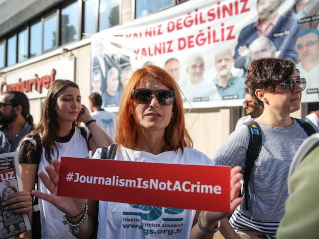 ISTANBUL, TURKEY - JULY 24: A protester holds up a banner outside the central Istanbul court during a protest against the trial of journalists and staff from Cumhuriyet newspaper on July 24, 2017, in Istanbul Turkey. Seventeen journalists and managers at Turkish opposition newspaper Cumhuriyet are facing trial on charges …