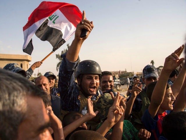 Members of Iraq's federal police force wave Iraq's national flag as they celebrate in the