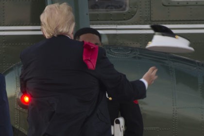US President Donald Trump tries to catch a hat that the wind had blown from the head of a