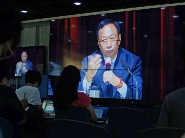 Journalists (in foreground) watch a large video screen showing Terry Gou of the Hon Hai gr