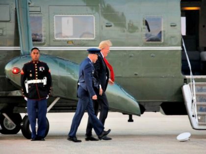 US-President-Donald-Trump-tries-to-catch-the-hat-of-a-Marine-that-flew-due-to-the-wind-dur