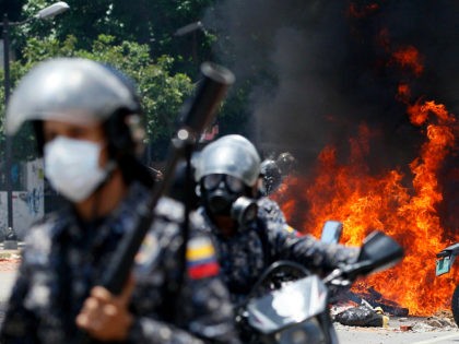 Venezuelan Bolivarian National police move away from the flames after an explosion at Altamira square during clashes against anti-government demonstrators in Caracas, Venezuela, Sunday, July 30, 2017. The explosion injured several officers and damaged several of their motorcycles. The officers were then seen throwing several privately owned motorcycles into the …