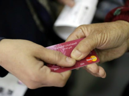 A Syrian refugee presents a World Food Programme debit card to a cashier in a Beirut shop on June 14, 2017