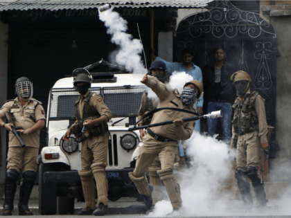 A policeman throws a tear gas shell at Kashmiri protesters demonstrating against Indian ru