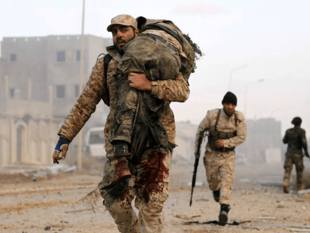 A member of the Libyan National Army (LNA) carries an injured comrade during fighting agai