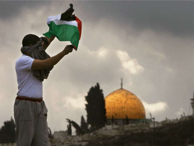 JERUSALEM, ISRAEL - FEBRUARY 16: A Palestinian waves a Palestinian flag as the Dome of the Rock is seen in the Background during clashes outside the Old City on February 16, 2007 in the Eastern district of Jerusalem. Islamic Prayers passed peacefully after about 3,000 police were deployed around the …