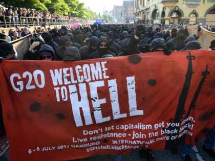 HAMBURG, GERMANY - JULY 06: Protesters dressed in all black hold up a banner as they take part in the 'Welcome to Hell' protest march on July 6, 2017 in Hamburg, Germany. Leaders of the G20 group of nations are arriving in Hamburg today for the July 7-8 economic summit …