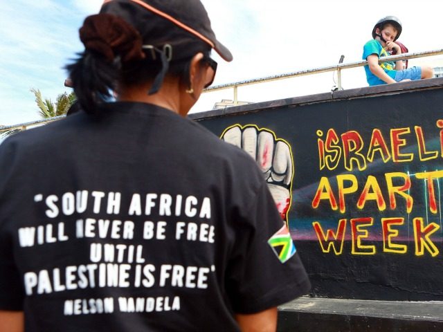 Palestinian activists stand infront of a graffiti as they participate in a protest against Israel at the north beach in Durban on March 10, 2013 ahead of the Israeli Apartheid Week (IAW) from March 11 to 17, 2013 in South Africa. The annual international series of events includes rallies, lectures, …