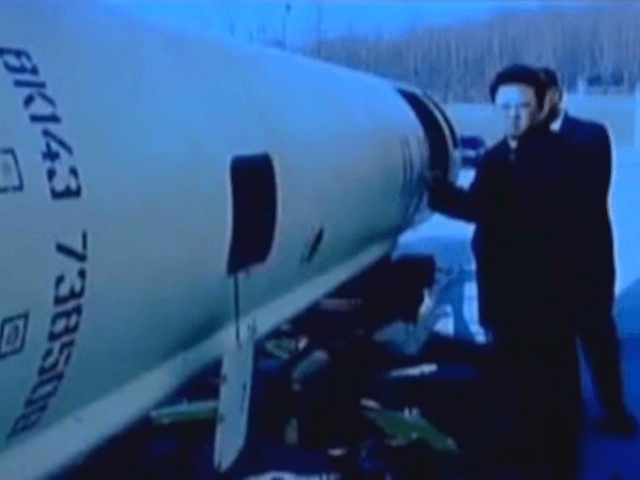 Former North Korean leader Kim Jong Il stands near what appears to be a Scud-B missile.