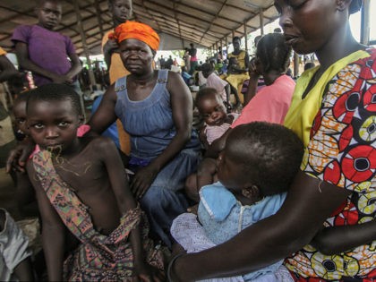PALABEK SETTLEMENT CAMP, NORTH UGANDA - MAY 2017: South Sudanese refugees Jessica and her niece Lillian wait with others at the Palabek refugee camp reception to be allocated their plot of land in Palabek Settlement camp, North Uganda, May 2017. Unaccompanied children are fleeing violent attacks in South Sudan, travelling …