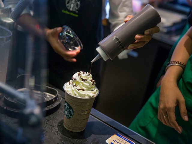 An employee pours syrup over whipped cream while preparing a coffee drink at a Starbucks Corp. coffee shop in Phnom Penh, Cambodia on Monday, Oct. 24, 2016. The Seattle-based coffee chain is expanding in Cambodia to tap the nation's rapid GDP growth. The share of the company's Asian revenue has …