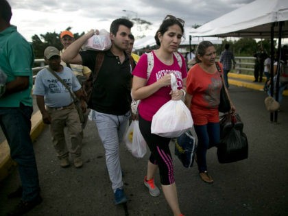 Venezuelans carrying their purchases return to their country through the Simon Bolivar bridge in Cucuta, Colombia, Sunday, July 17, 2016. Tens of thousands of Venezuelans crossed the border into Colombia on Sunday to hunt for food and medicine that are in short supply at home. It's the second weekend in …