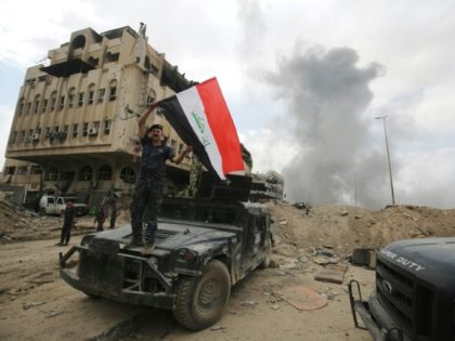 A member of the Iraqi federal police waves the national flag in the Old City of Mosul on July 8, 2017