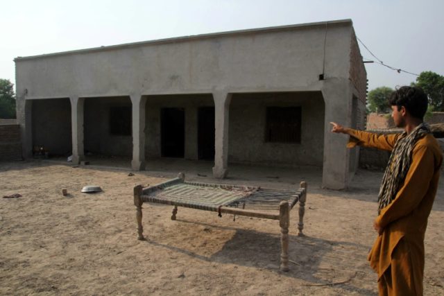 A Pakistani villager poses as he points to a house where a teenage girl was raped in the n