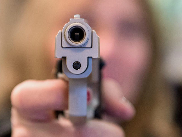 A woman points a blank gun at the photographers camera at a weapons shop in Frankfurt, Ger