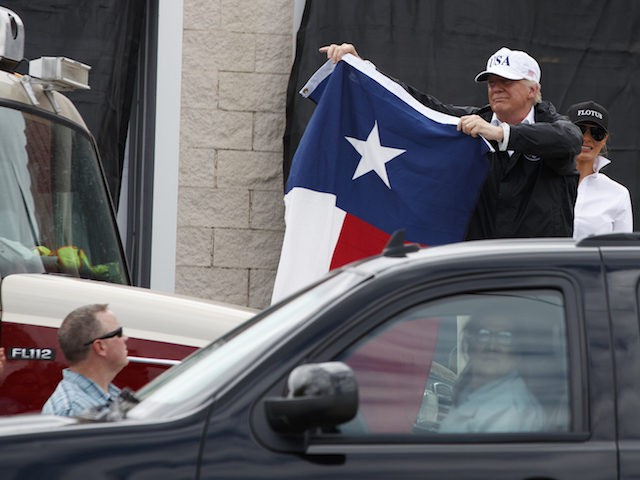 President Donald Trump, accompanied by first lady Melania Trump, holds up a Texas flag after speaking with supporters outside Firehouse 5 in Corpus Christi, Texas, Tuesday, Aug. 29, 2017, following a briefing on Harvey relief efforts. (AP Photo/Evan Vucci)