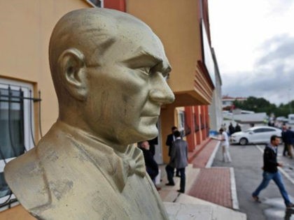 People walk by a bust of Turkish Republic founder Mustafa Kemal Ataturk, at the school that will be the polling station where Turkey's President Recep Tayyip Erdogan will vote later in the day, in Istanbul, Turkey, Sunday, June 7, 2015. Turkey is holding Sunday a general election and approximately 56 …