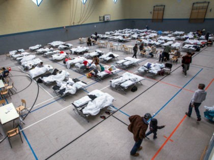 Migrants walk next to camp beds in a makeshift refugee shelter near a first registration center for migrants in a gym in Stern-Buchholz, northern Germany, on September 7, 2015. German Chancellor Angela Merkel said the record refugee influx to Europe's biggest economy will change the country, which was now seen …