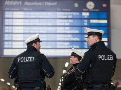 Policemen stand under a schedule board on March 10, 2017 in Duesseldorf, western Germany, one day after German police have arrested an axe-wielding attacker after he after he injured seven people at the main train station of the city. German police have arrested an axe-wielding attacker believed to be suffering …
