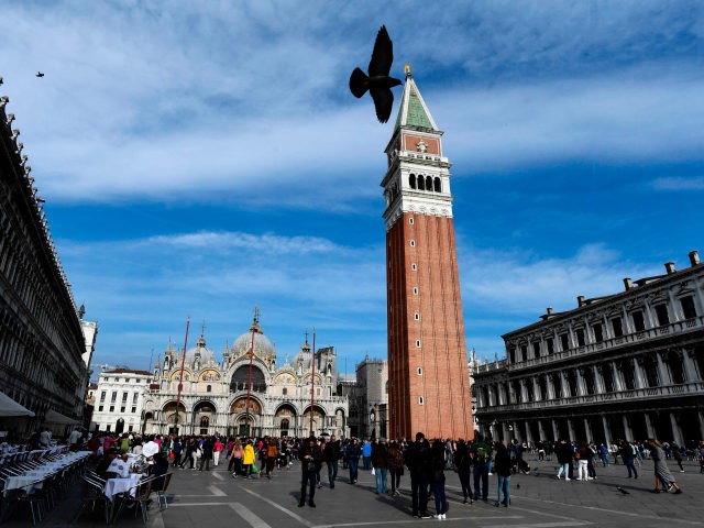 Tourist walk across the Piazza San Marco with the Saint Mark's Basilica and the San M