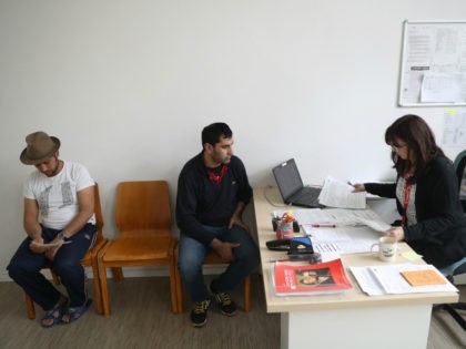 BERLIN, GERMANY - MAY 03: Shelter employee Katrin Krug (R) assists resident Abdul Hakim (C) from Syria with bureaucratic paperwork as resident Mohammad Nader Mohamedi (L) from Afghanistan waits his turn in the counselling center at a shelter for refugees and migrants in Marienfelde district on May 3, 2017 in …