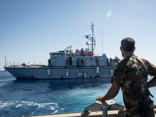 A Libyan coastguard looks towards a ship as he patrols the area at sea between Sabratha an