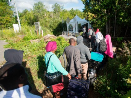 TOPSHOT - A long line of asylum seekers wait to illegally cross the Canada/US border near