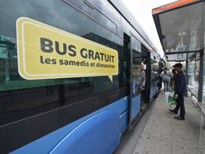 People wait to board a bus advertising a free bus service on saturdays and sundays in the