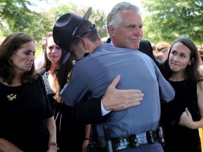 Virginia Governor Terry McAuliffe is embraced by a Virginia State Police trooper after he and his wife Dorothy McAuliffe (L) attended the funeral for Trooper-Pilot Berke M.M. Bates at Saint Paul's Baptist Church August 18, 2017 in Richmond, Virginia. Bates and Lieutenant Pilot Jay Cullen were killed when their Bell …