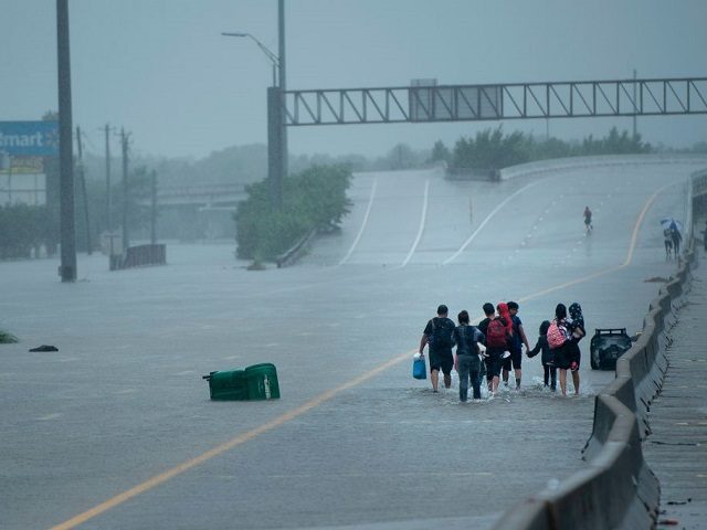 Evacuation residents from the Meyerland area walk onto an I-610 overpass for further help during the aftermath of Hurricane Harvey August 27, 2017 in Houston, Texas. Hurricane Harvey left a trail of devastation Saturday after the most powerful storm to hit the US mainland in over a decade slammed into …