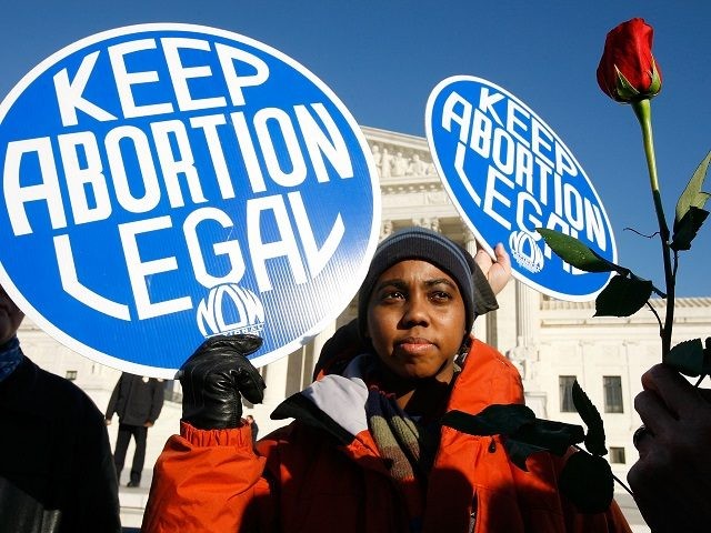 WASHINGTON - JANUARY 22: Local pro-choice activist Lisa King holds a sign in front of the U.S. Supreme Court as a pro-life activist holds a rose nearby during the annual "March for Life" event January 22, 2009 in Washington, DC. The event was to mark the anniversary of the 1973 …