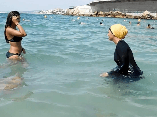 In this image taken from video, Nesrine Kenza who says she is happy to be free to wear a burkini, and two unidentified friends wade into the sea, in Marseille, France, Monday Aug. 29, 2016.