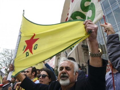A man holds a flag of YPG, a Syria-based Kurdish militant group, during a protest against Turkish President Recep Tayyip Erdogan in front of Brookings Institution in Washington, Thursday, March 31, 2016, where President Erdogan was speaking. (AP Photo/Sait Serkan Gurbuz)