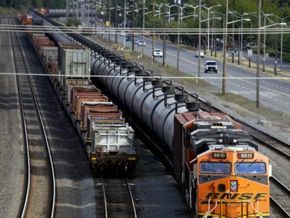 FILE - In this July 27, 2015, file photo, traffic passes one of two mile-long oil trains parked near the King County Airport in Seattle. More crude oil than ever is expected to move through Washington state, particularly since the Canadian government approved the Kinder Morgan pipeline project that will …