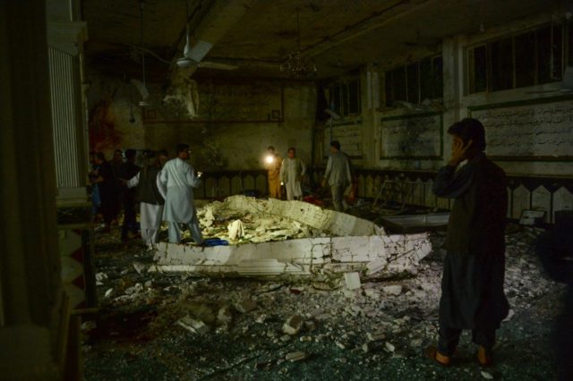 Afghan security personel inspect the site of a suicide bomb attack at a Shiite mosque in H