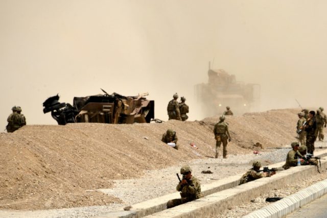 US soldiers keep watch near the wreckage of their vehicle at the site of a Taliban suicide