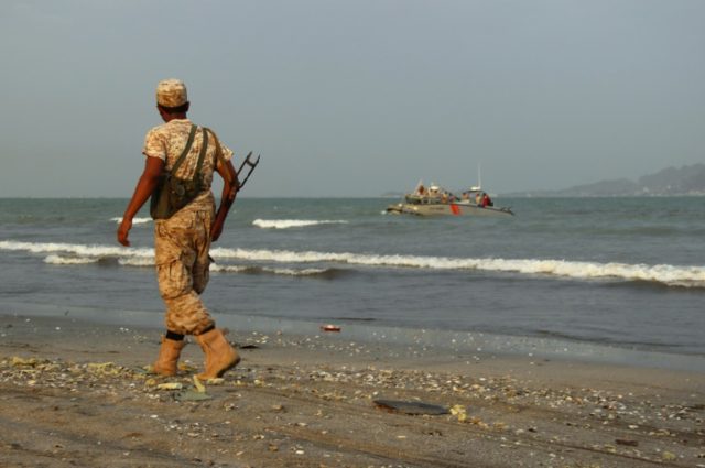 A pro-government forces soldier walks along the beach in the southern coastal city of Aden