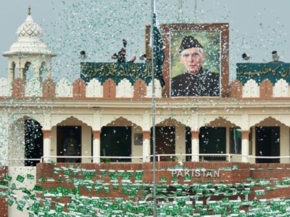 The portrait of Muhammad Ali Jinnah is seen at the India-Pakistan Wagah border post as a Pakistani Ranger (top) unfurls the national flag on Independence Day