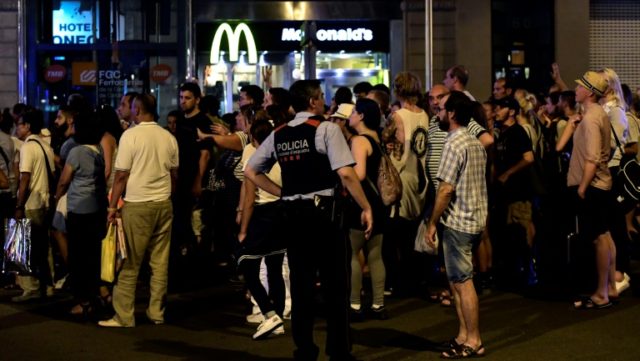 Tourists wait for the police to allow them to come back to their hotel on Las Ramblas boul