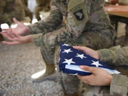 A U.S. soldier holds a flag in Afghanistan.
