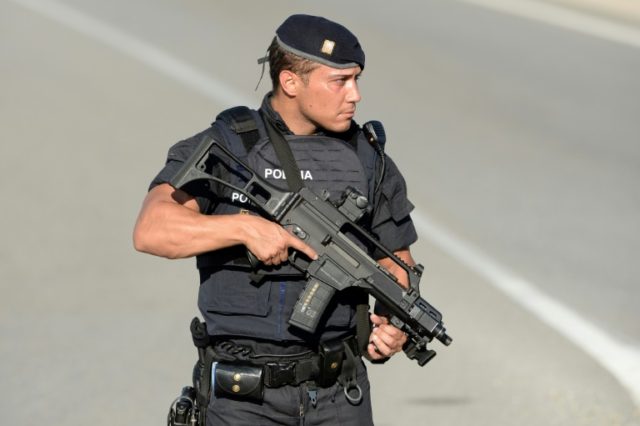 An armed Spanish policeman stands guard at the site where Moroccan suspect Younes Abouyaaq