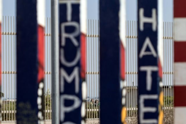 Border Patrol agents are seen through the border fence detaining two people at the Border