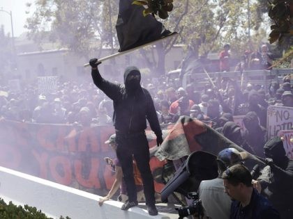 An anti-fascist demonstrator jumps over a barricade during a free speech rally Sunday, Aug
