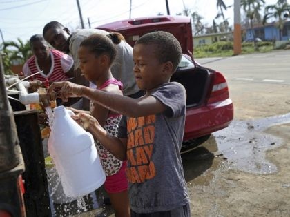 Children fill up bottles with water at a water distribution point, in the aftermath of Hurricane Maria in Loiza, Puerto Rico, Sunday, Sept. 24, 2017. Federal aid is racing to stem a growing humanitarian crisis in towns left without fresh water, fuel, electricity or phone service by the hurricane. (AP …
