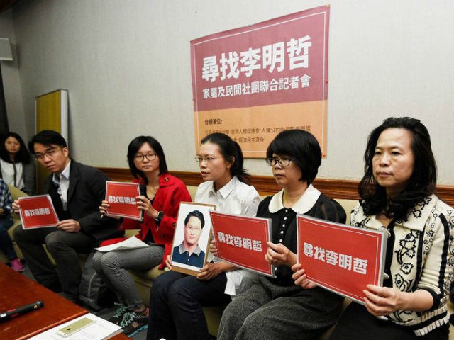 Lee Ching-yu, third from right, holds a photo of her missing husband and pro-democracy act