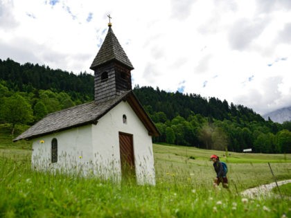 GARMISCH-PARTENKIRCHEN, GERMANY - JUNE 24: A hiker walks towards a small chapel in the Bav