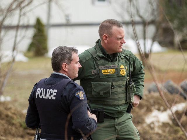 An Royal Canadian Mounted Police officer speaks with a US Boarder Patrol agent at an uncon