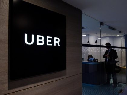 Uber signage is seen as an employee stands in the entrance of the ride-hailing giant's office in Hong Kong on March 10, 2017. Uber hit back at Hong Kong authorities on March 10 after five of its drivers were found guilty of operating without proper licences, in yet another blow …